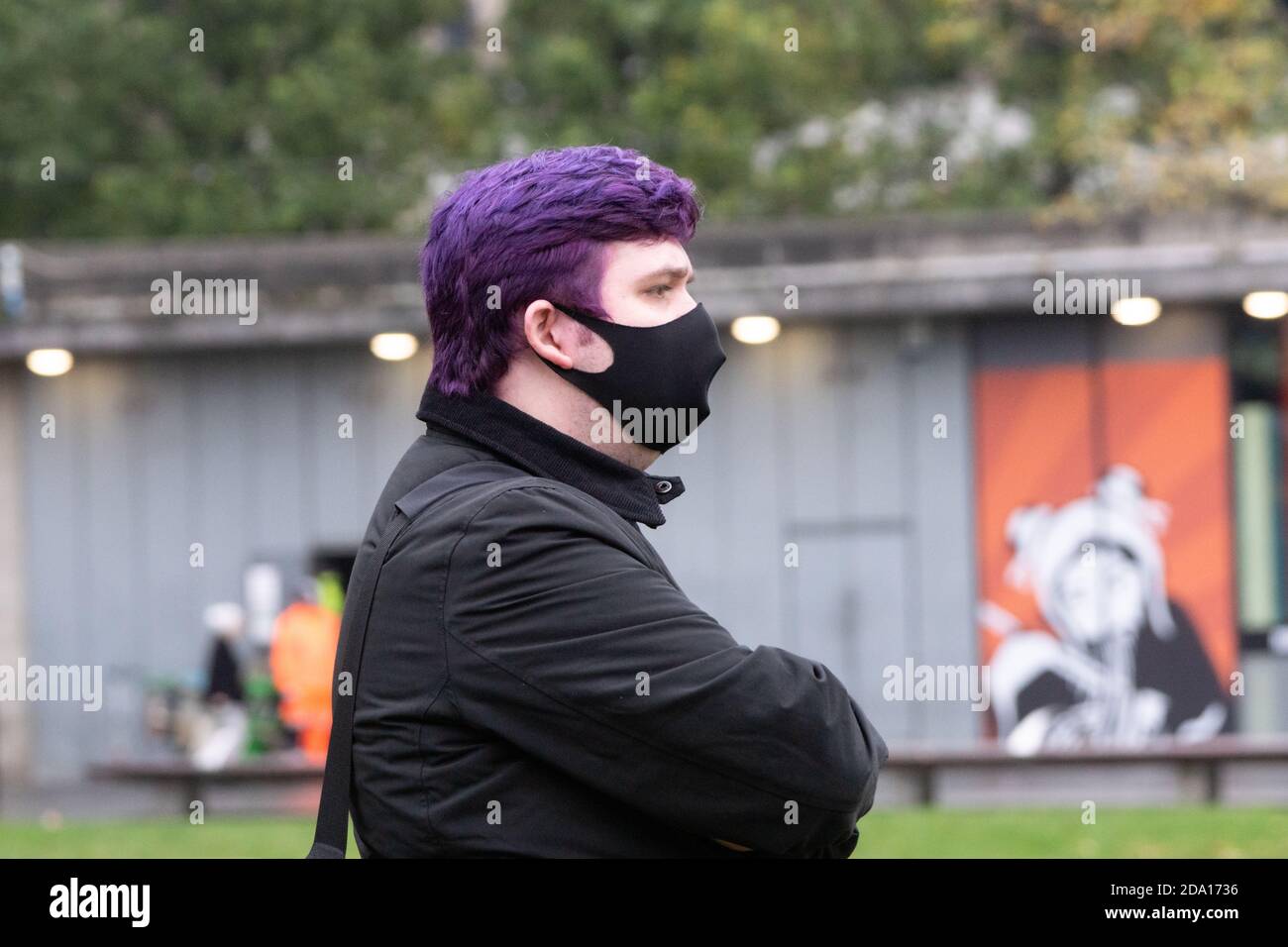 Jeune homme aux cheveux violets portant un masque noir à l'extérieur, observant la manifestation anti-verrouillage Manchester 08-11-2020, Covid, covid19, 2020 Banque D'Images
