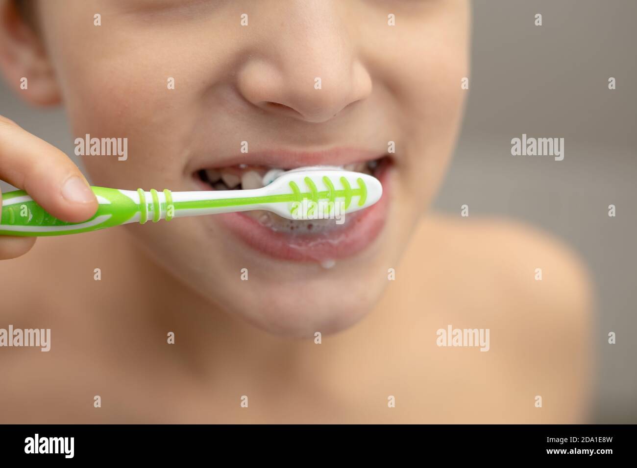L'éducation dentaire dans la famille, un garçon avec joie 10 ans, se lavant les dents avec du dentifrice et une brosse à dents dans la salle de bains. Concept de dents saines Banque D'Images