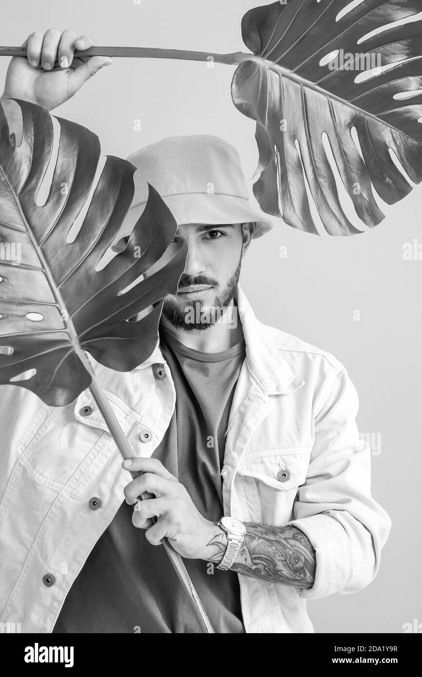 Portrait noir et blanc de jeune homme à la mode avec tropical laisse sur fond clair Banque D'Images