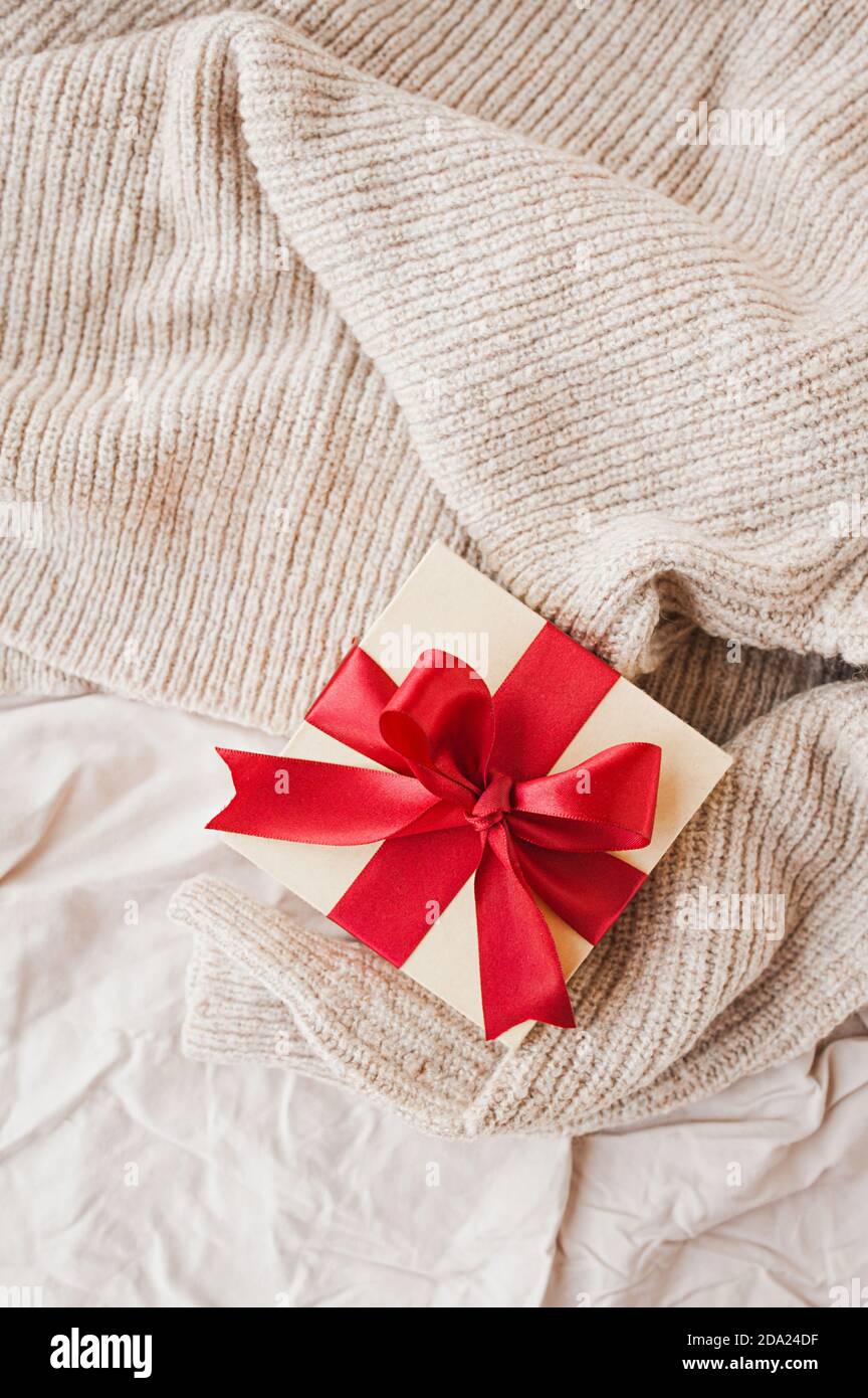 boîte carrée élégante beige avec ruban de satin rouge festif couverture en crumettes beige pour une mise au point sélective Banque D'Images