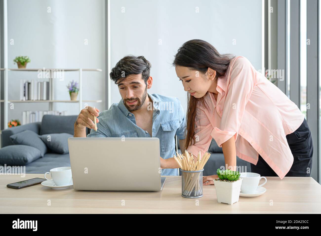 Joyeux et détendu style de vie de jeune amoureux de couple portant une robe décontractée ensemble travailler sur ordinateur portable ordinateur portable dans le salon à la maison. Positif RE Banque D'Images