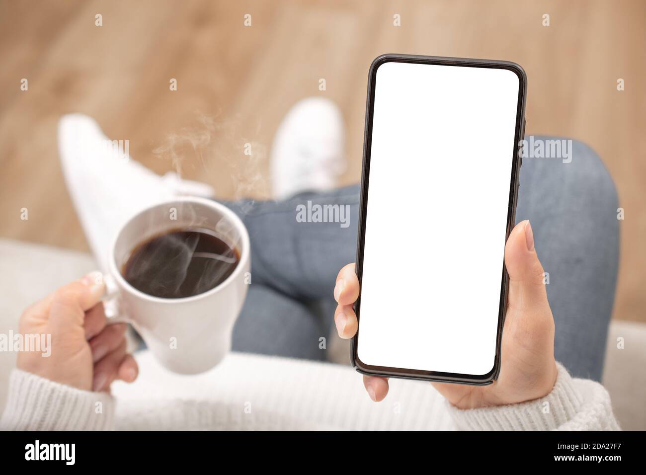 Image de maquette d'une femme tenant un téléphone portable noir avec écran blanc vierge dans un café. Vue rognée des mains d'une femme tenant un smartphone avec une co vierge Banque D'Images