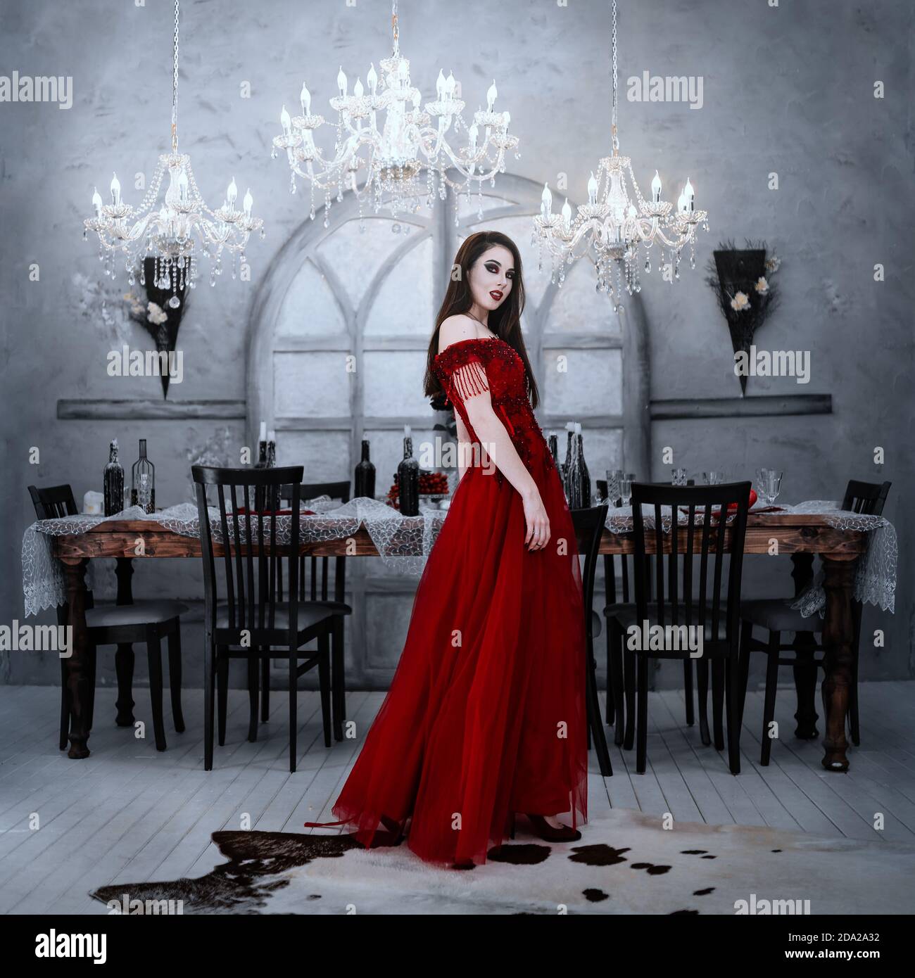 Vampire femme assoiffée de sang en robe rouge. Intérieur médiéval Banque D'Images