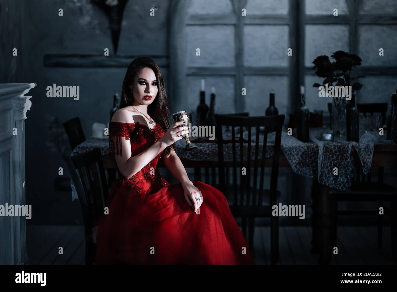 Vampire femme assoiffée de sang en robe rouge. Intérieur médiéval Banque D'Images