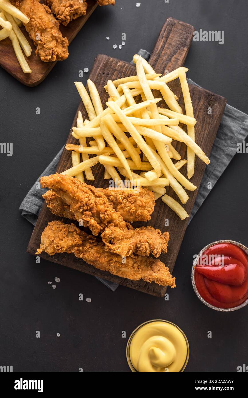 Poisson et frites. Filet de poisson frits et frites servies sur table noire avec sauces. Cuisine de rue britannique traditionnelle, vue sur le dessus, espace copie. Banque D'Images
