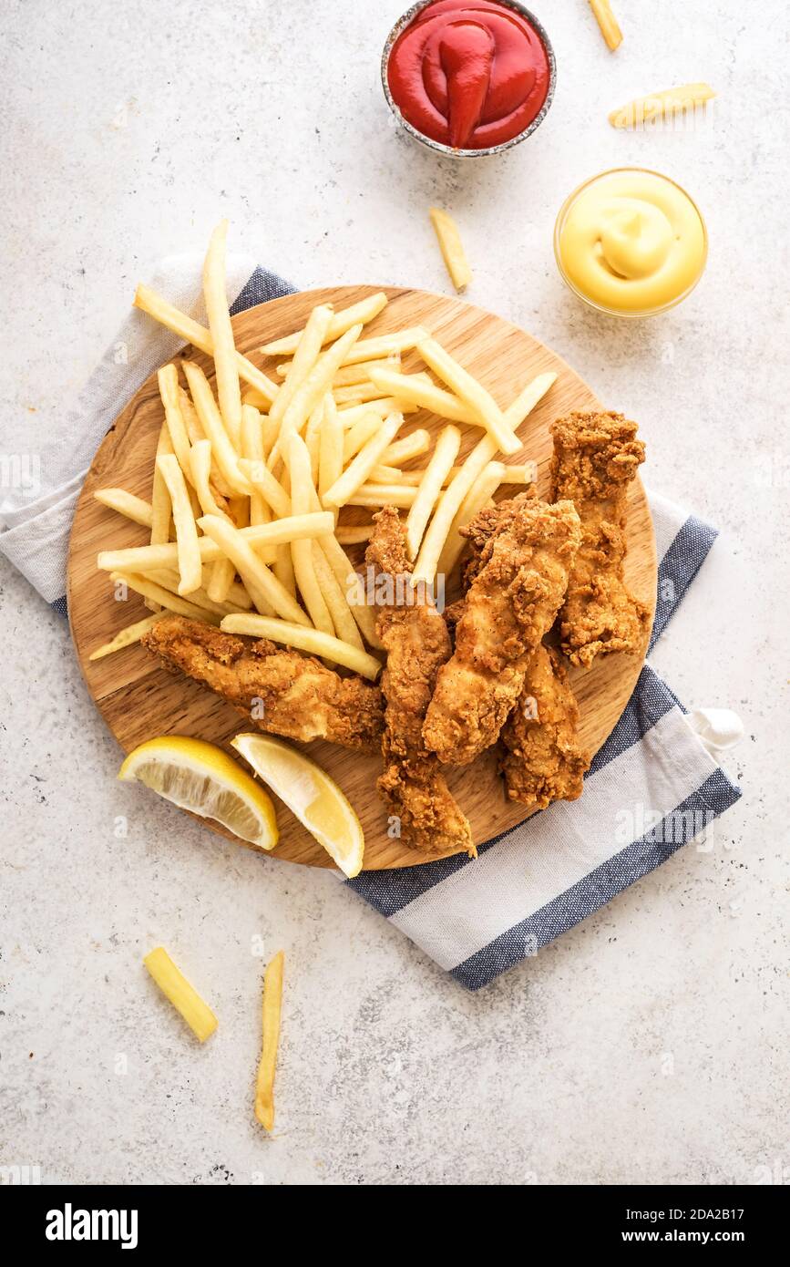 Poisson et frites. Filet de poisson frits et frites sur fond blanc avec sauces. Cuisine de rue britannique traditionnelle, vue sur le dessus, espace copie. Banque D'Images