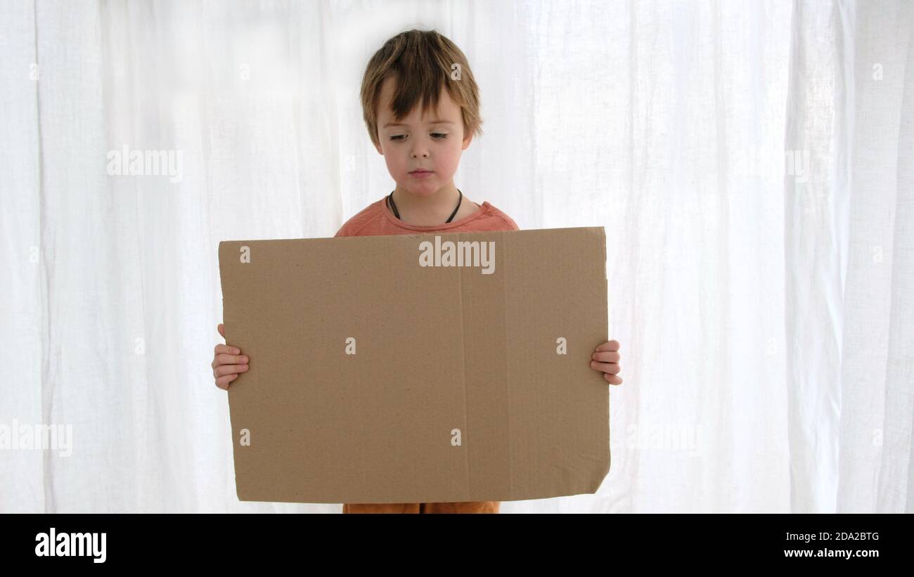 Le garçon contrarié tient la feuille de carton avec de l'espace pour le gabarit Banque D'Images