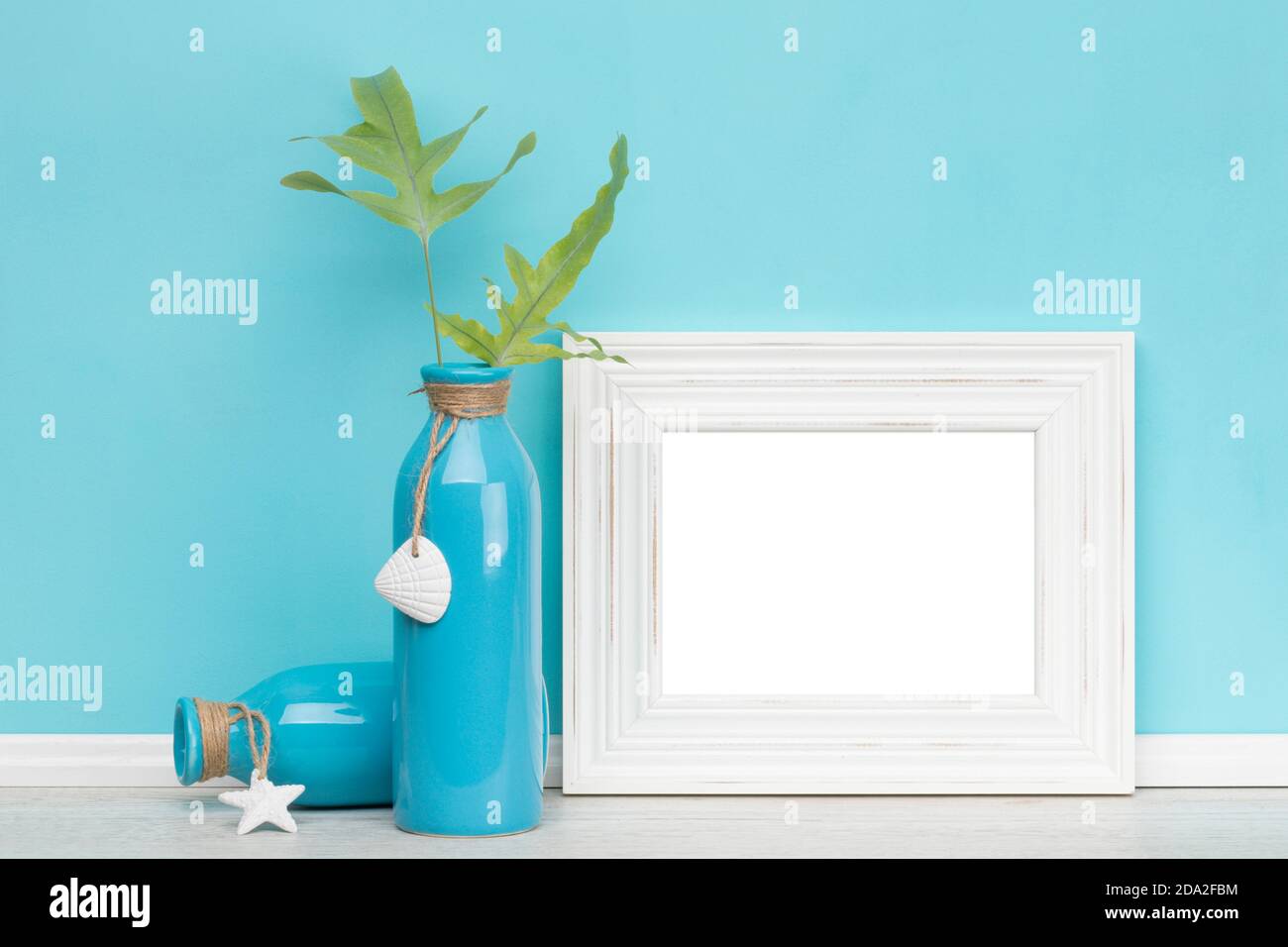 Maquette de cadre horizontal chic blanc avec deux vases bleus, des feuilles de fougères et un mur turquoise. Zone d'image vierge isolée avec découpe p Banque D'Images