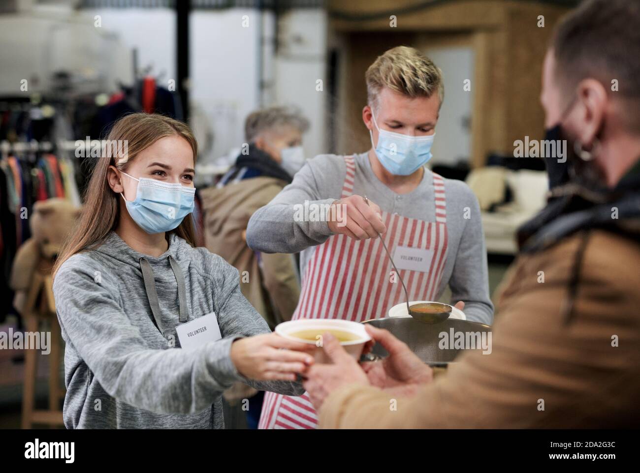 Bénévoles servant de la soupe chaude pour les malades et les sans-abri dans un centre de dons de charité communautaire, une banque alimentaire et le concept de coronavirus. Banque D'Images