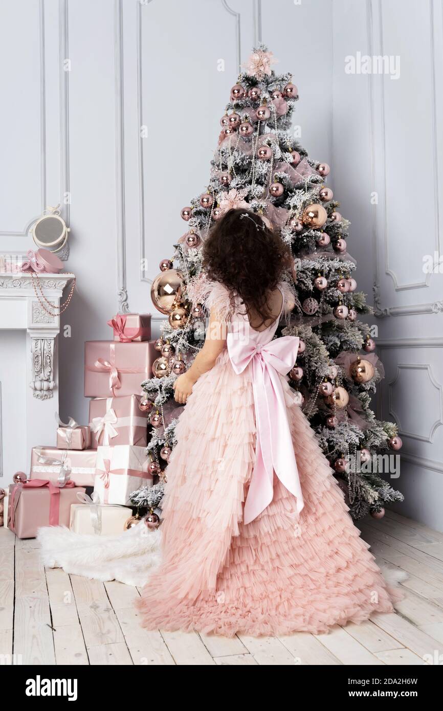 Petite fille dans une belle robe décorent l'arbre de Noël Banque D'Images