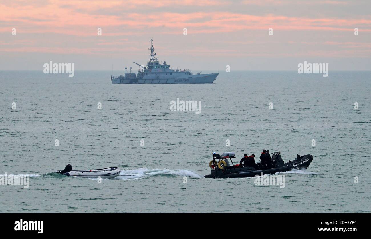 Un petit bateau est remorqué par un navire de la Force frontalière alors que le chercheur de la Force frontalière (en haut) patrouille le littoral à la suite d'un incident impliquant un petit bateau dans la Manche plus tôt ce matin. Banque D'Images