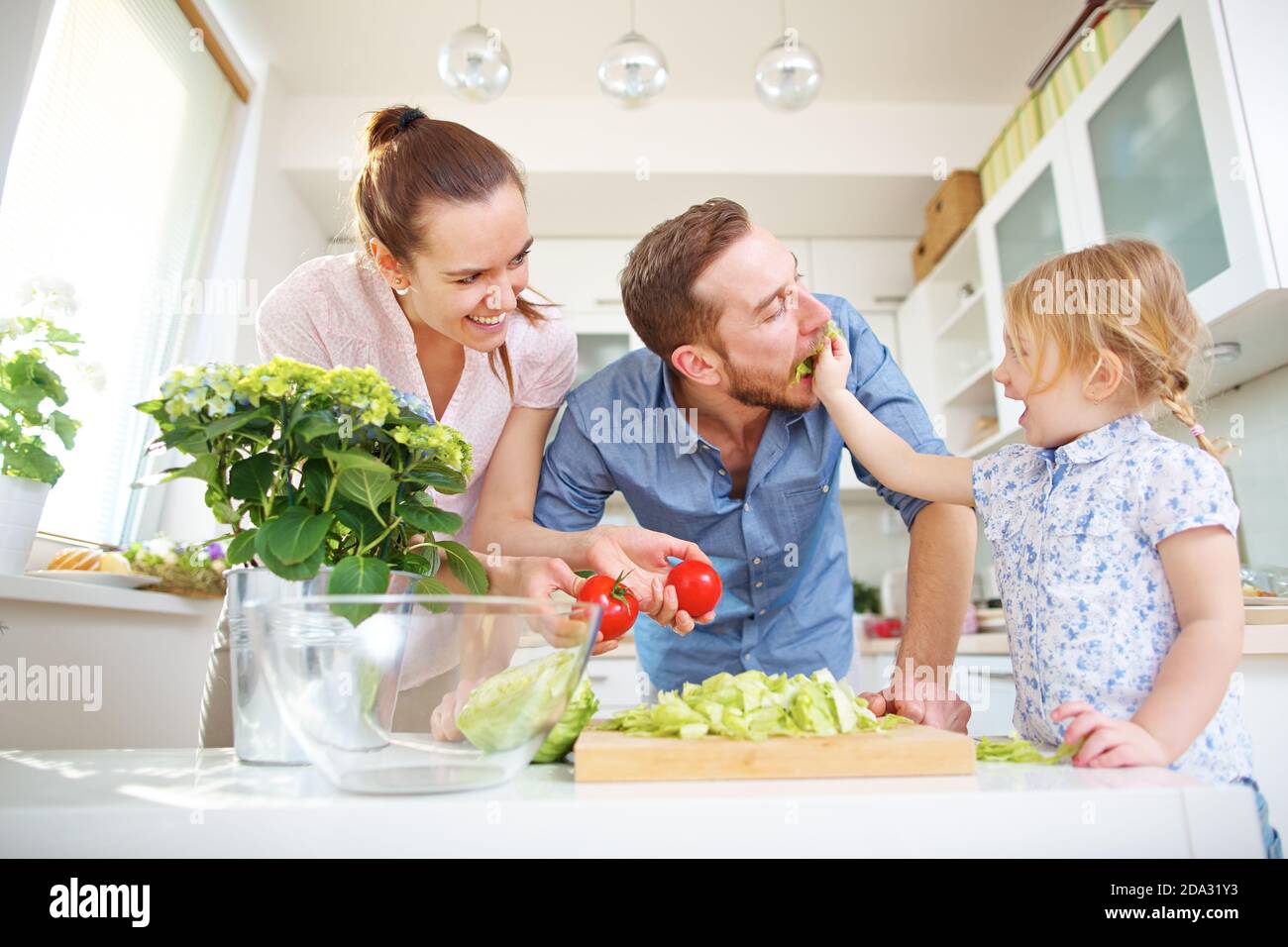 Une famille heureuse veut manger de la salade de tomates fraîche dans le cuisine Banque D'Images