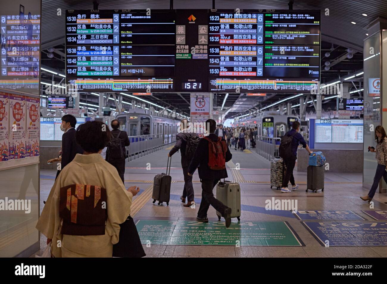 Osaka, Japon, avril 2018. Personnes transportant des valises sous le panneau lumineux informatif à la gare de Namba. Banque D'Images