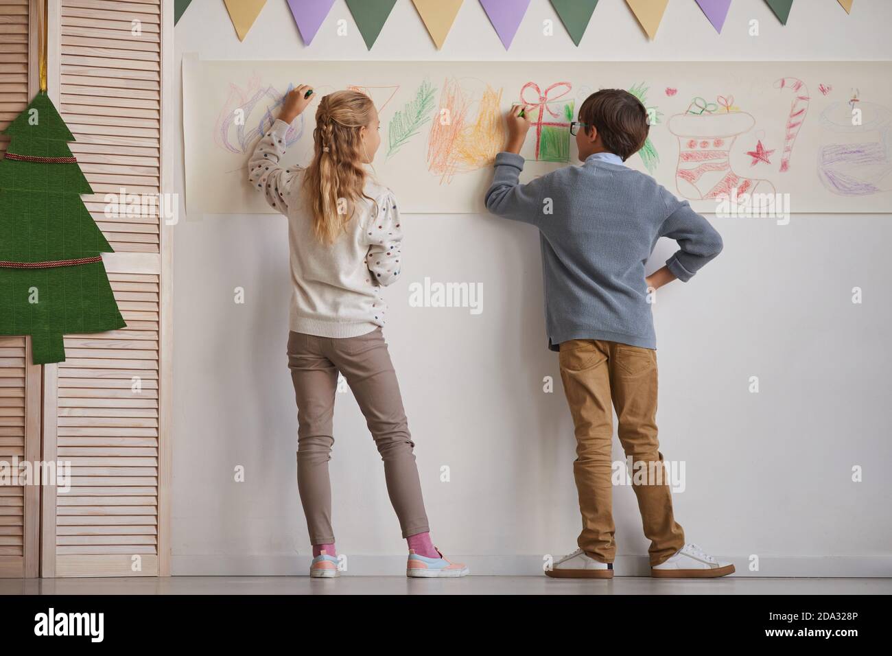 Vue arrière sur toute la longueur du garçon et de la fille dessin sur les murs tout en appréciant la classe d'art à l'école, l'espace de copie Banque D'Images