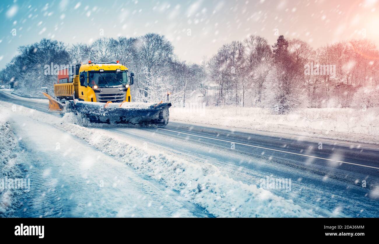 Chasse-neige camion nettoyant la route enneigée en tempête de neige Banque D'Images