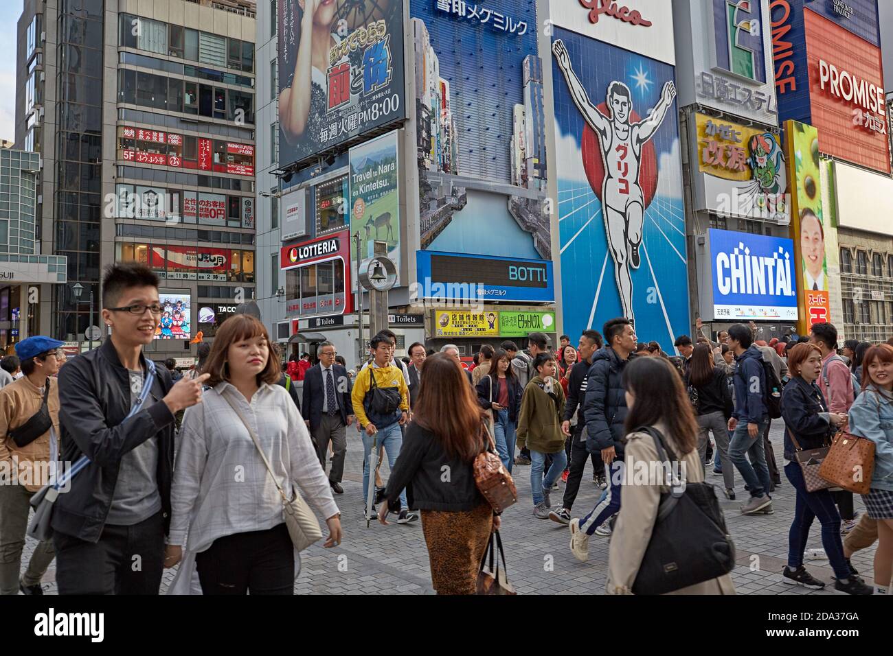 Osaka, Japon, avril 2018. Personnes marchant près du panneau lumineux de l'homme de course Glico à Dotombori, le plus célèbre monument de la ville. Banque D'Images