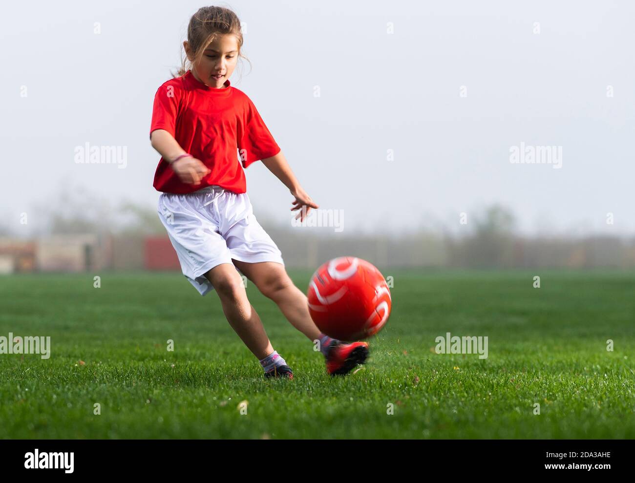 Fille lance un ballon de football sur un terrain de football Banque D'Images