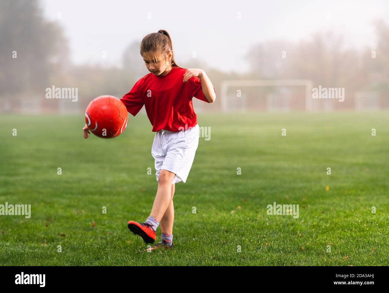 Fille lance un ballon de football sur un terrain de football Banque D'Images