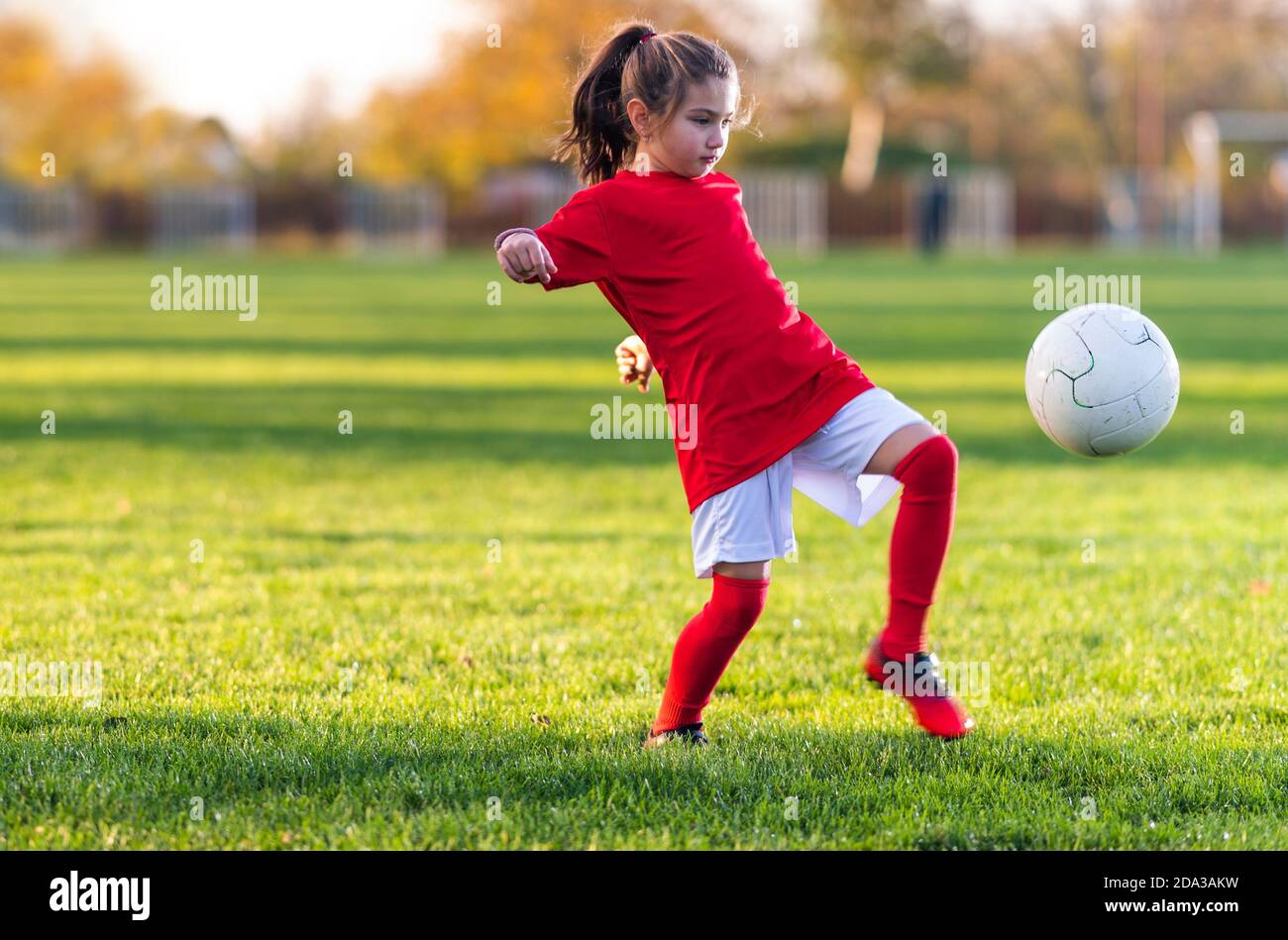 Fille lance un ballon de football sur un terrain de football Banque D'Images