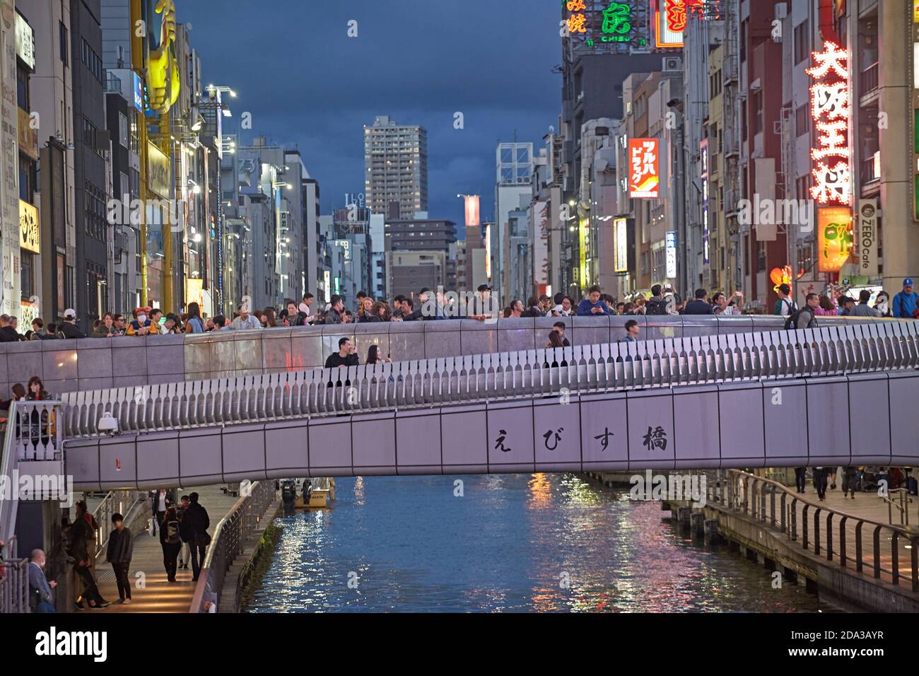 Osaka, Japon, avril 2018. Personnes traversant le pont Ebisu sur le canal Dontonbori au coucher du soleil. Banque D'Images