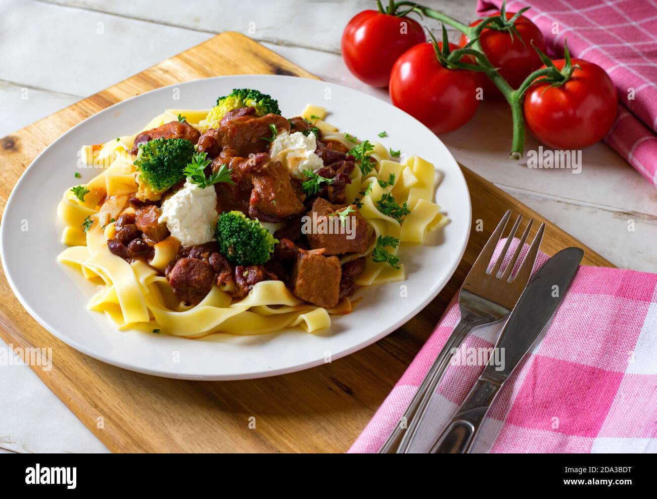 délicieux goulash de porc avec garniture à la crème aigre et pâtes sur une plaque Banque D'Images