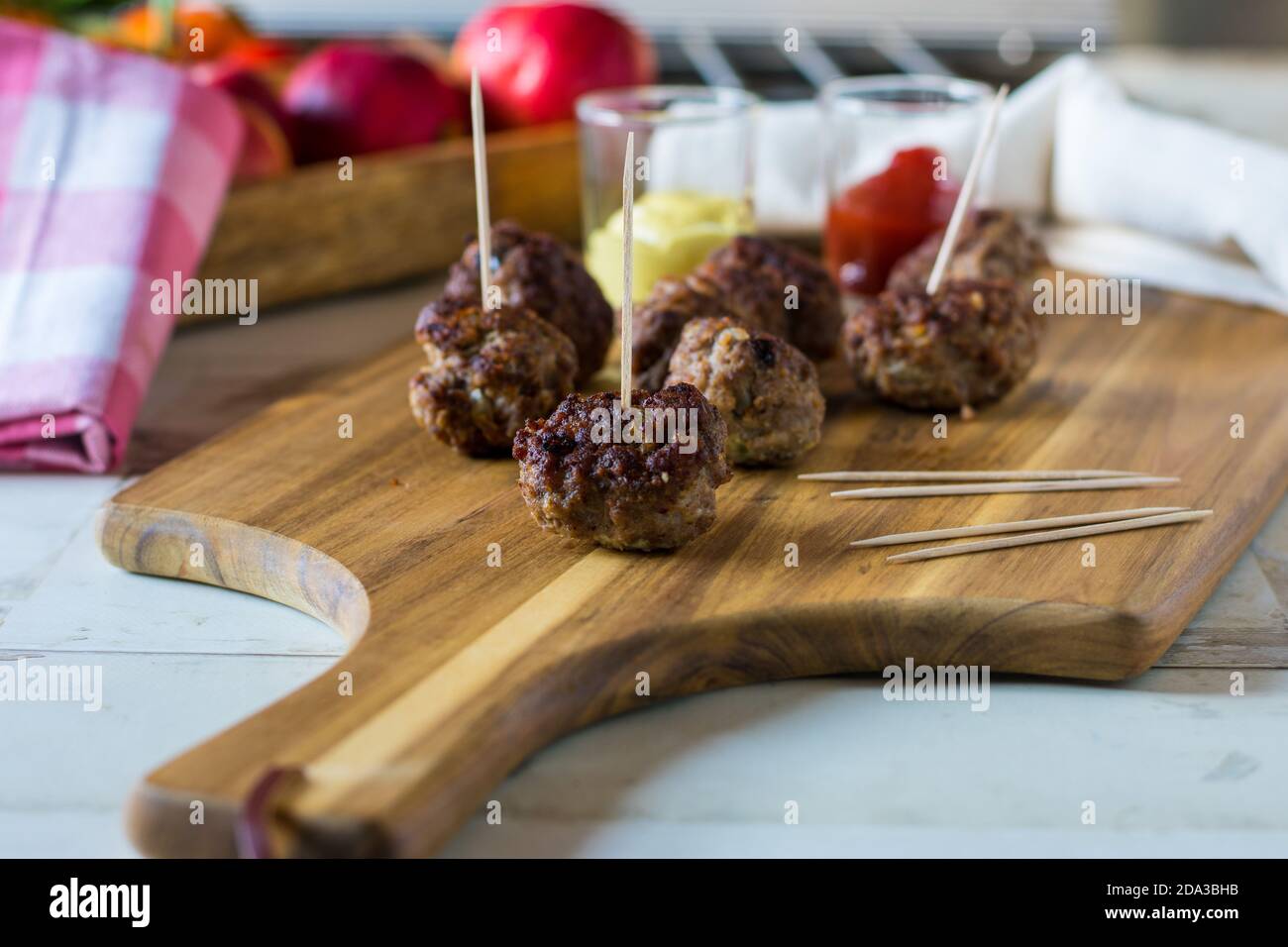 boulettes de viande avec cure-dents servies comme nourriture pour les doigts avec ketchup et moutarde sur une planche en bois Banque D'Images