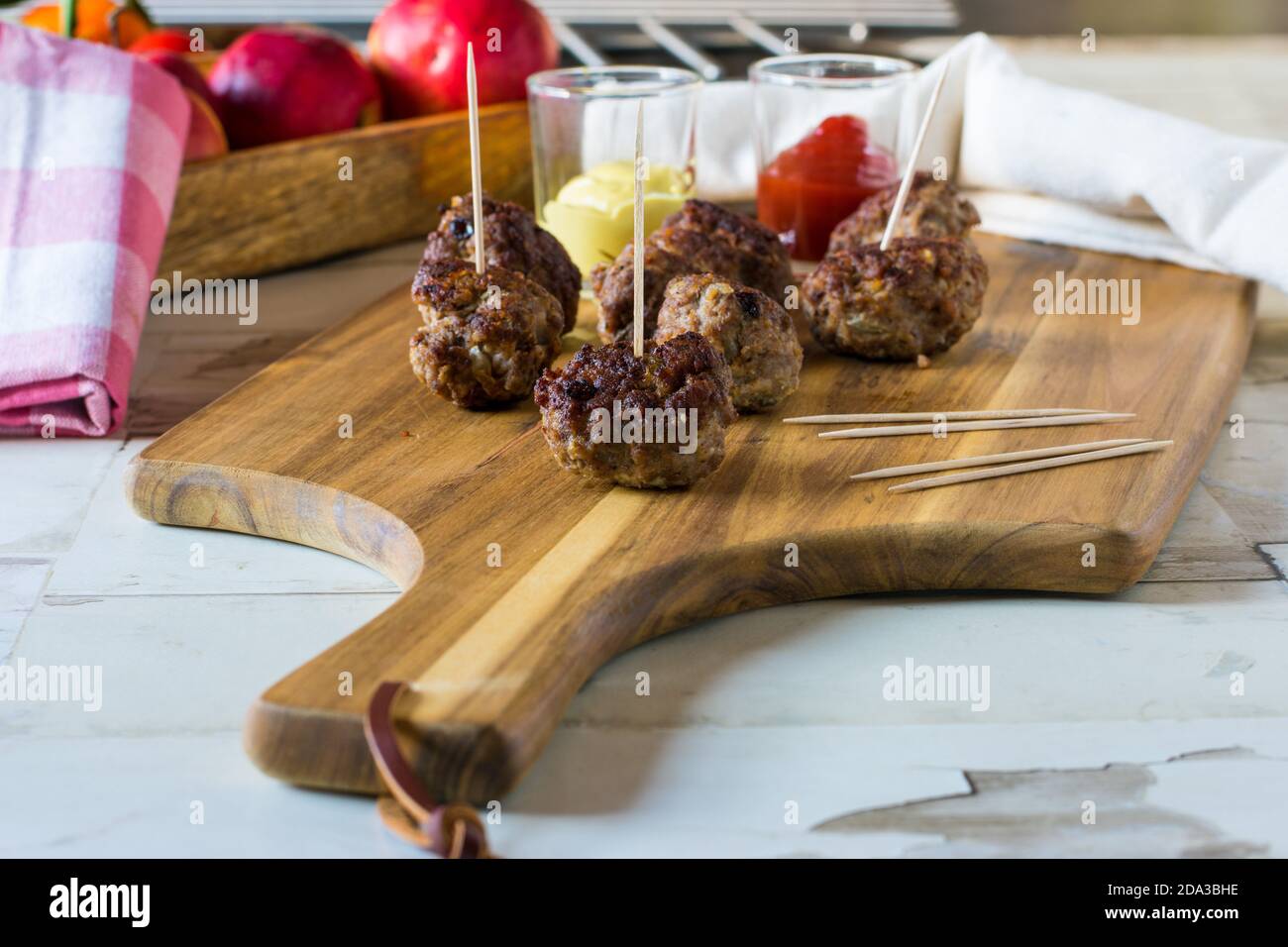 boulettes de viande avec cure-dents servies comme nourriture pour les doigts avec ketchup et moutarde sur une planche en bois Banque D'Images
