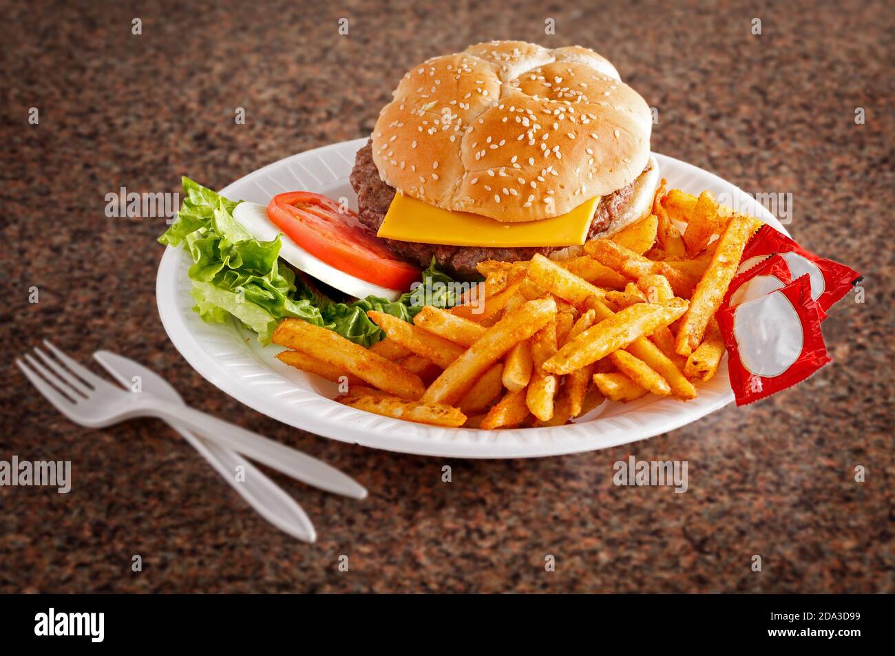 Cheeseburger américain et frites avec sachets de ketchup sur une surface en granit avec un espace de copie Banque D'Images