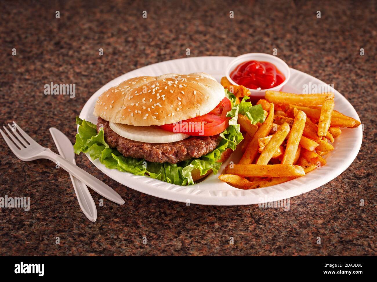 Hamburger de style américain sur un pain de graines de sésame avec des français frites et ketchup sur une surface en granit Banque D'Images