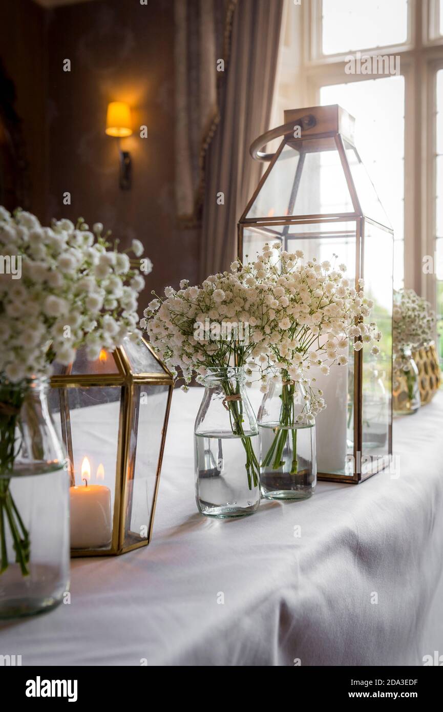 Fleurs en bouteilles de lait en verre sur une table lors d'une réception de mariage. Banque D'Images