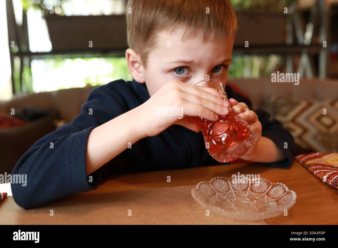 Un enfant boit du thé à l'hibiscus dans un restaurant Banque D'Images