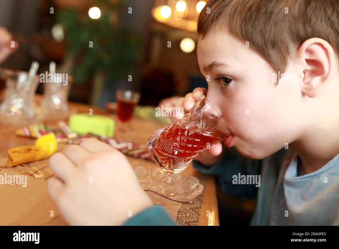 Un enfant boit du thé à l'hibiscus dans un restaurant Banque D'Images
