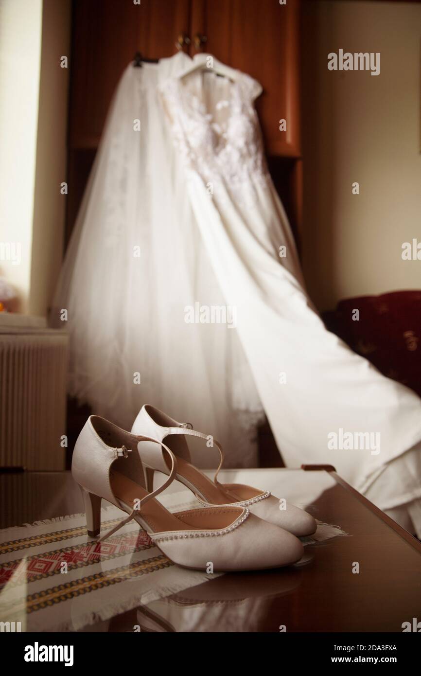 Des chaussures de mariage blanches avec une robe de mariage blanche l'arrière-plan Banque D'Images