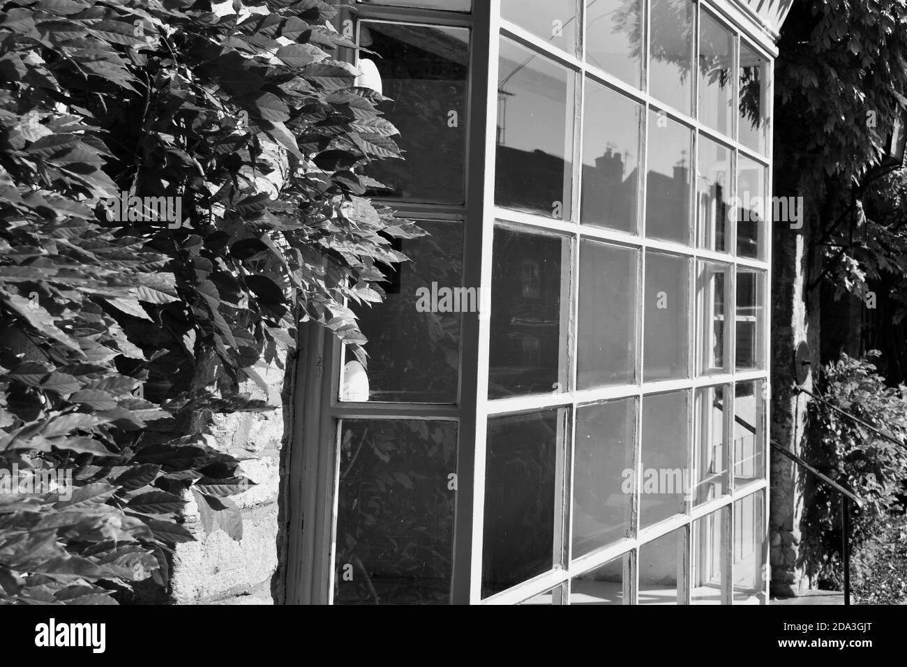 image en noir et blanc d'une vue de côté rapprochée de fenêtre d'image ancienne avec plusieurs panneaux de verre vider le bâtiment à la lumière du soleil Banque D'Images