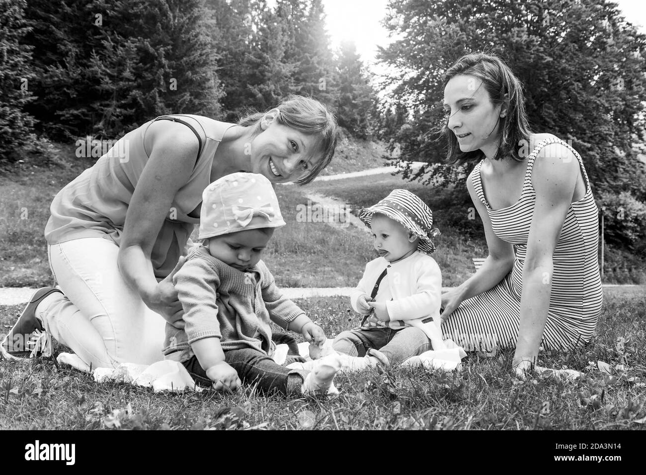 Deux amies qui profitent d'un pique-nique dans un beau soleil Jour avec leurs petites filles - les femmes assis avec peu jeunes filles sur l'herbe dans le mountai Banque D'Images