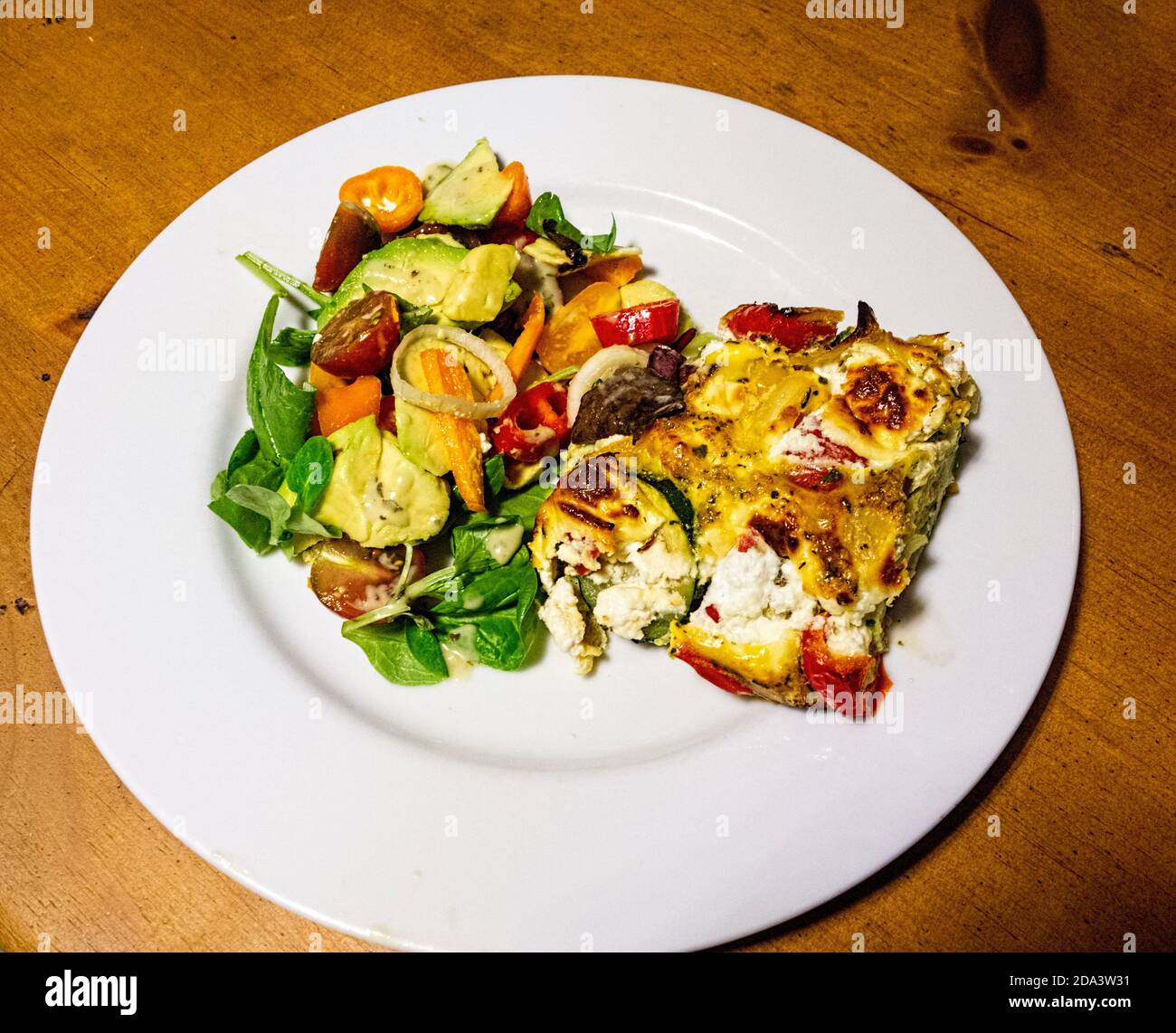 Fromage de chèvre Frittata fait avec des courgettes de poivre rouge et des œufs avec salade mélangée sur assiette blanche Banque D'Images