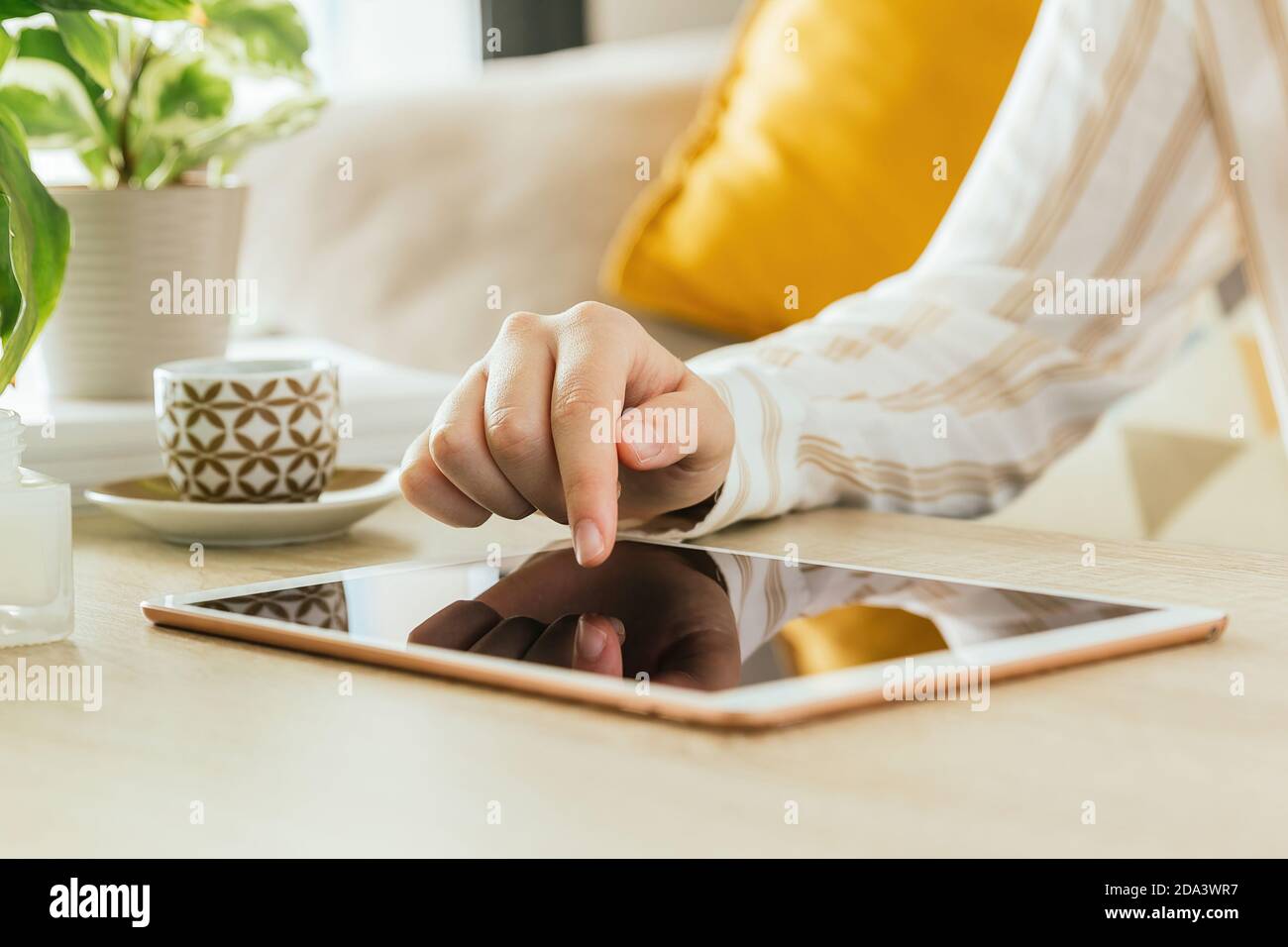 Photo de la main d'une femme utilisant une tablette la table dans le salon Banque D'Images