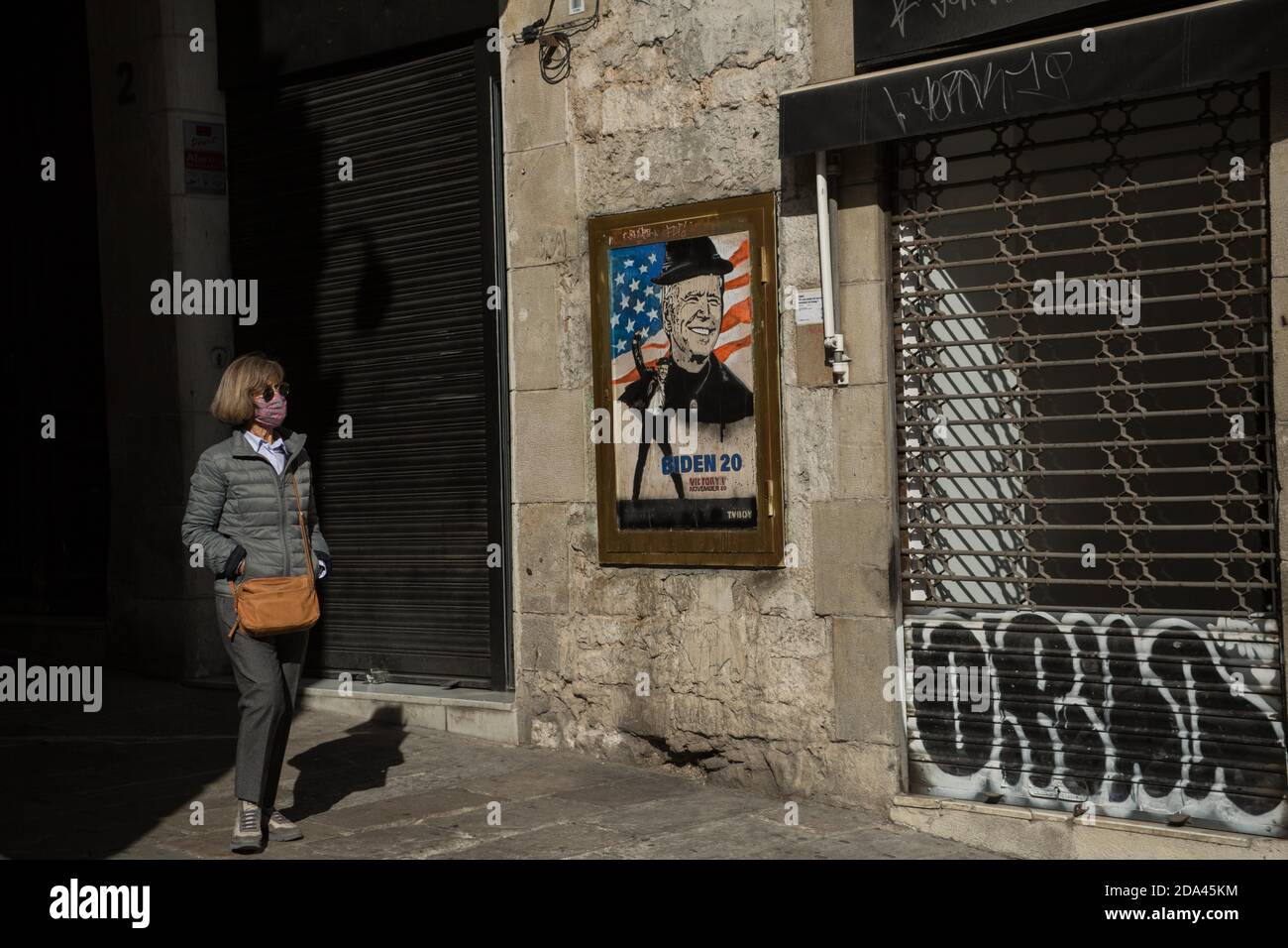 Barcelone, Espagne. 9 novembre 2020. Une femme portant un masque passe devant une œuvre de l'artiste espagnol TVBOY dans la rue de Barcelone, après la victoire du démocrate Joe Biden aux élections présidentielles américaines. Credit: Thiago PrudÃªNcio/SOPA Images/ZUMA Wire/Alay Live News Banque D'Images