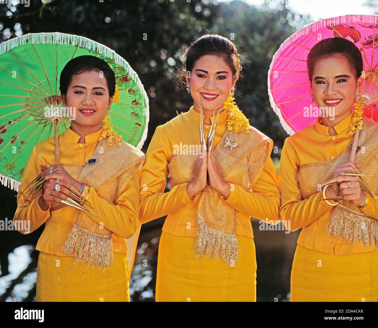 Thaïlande. Nakhon Pathom. Jardin de roses. Trois jeunes femmes danseuses traditionnelles de doigt posant dans le jardin. Banque D'Images