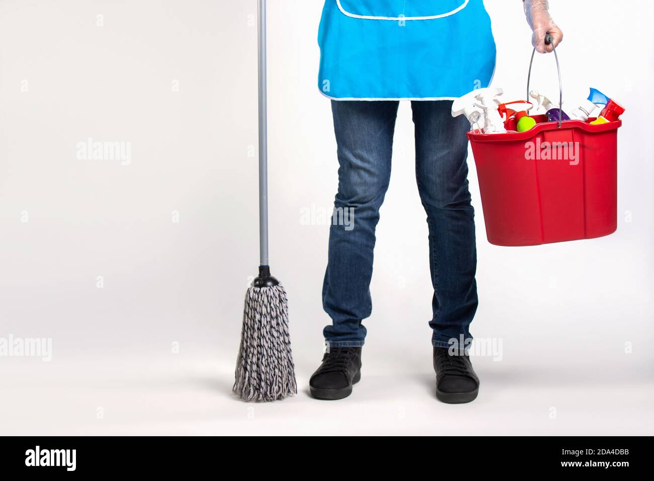 Égalité des sexes. Pieds d'un homme et dans les mains d'une vadrouille et d'un seau de produits de nettoyage. Photo sur fond blanc avec espace vide. Banque D'Images