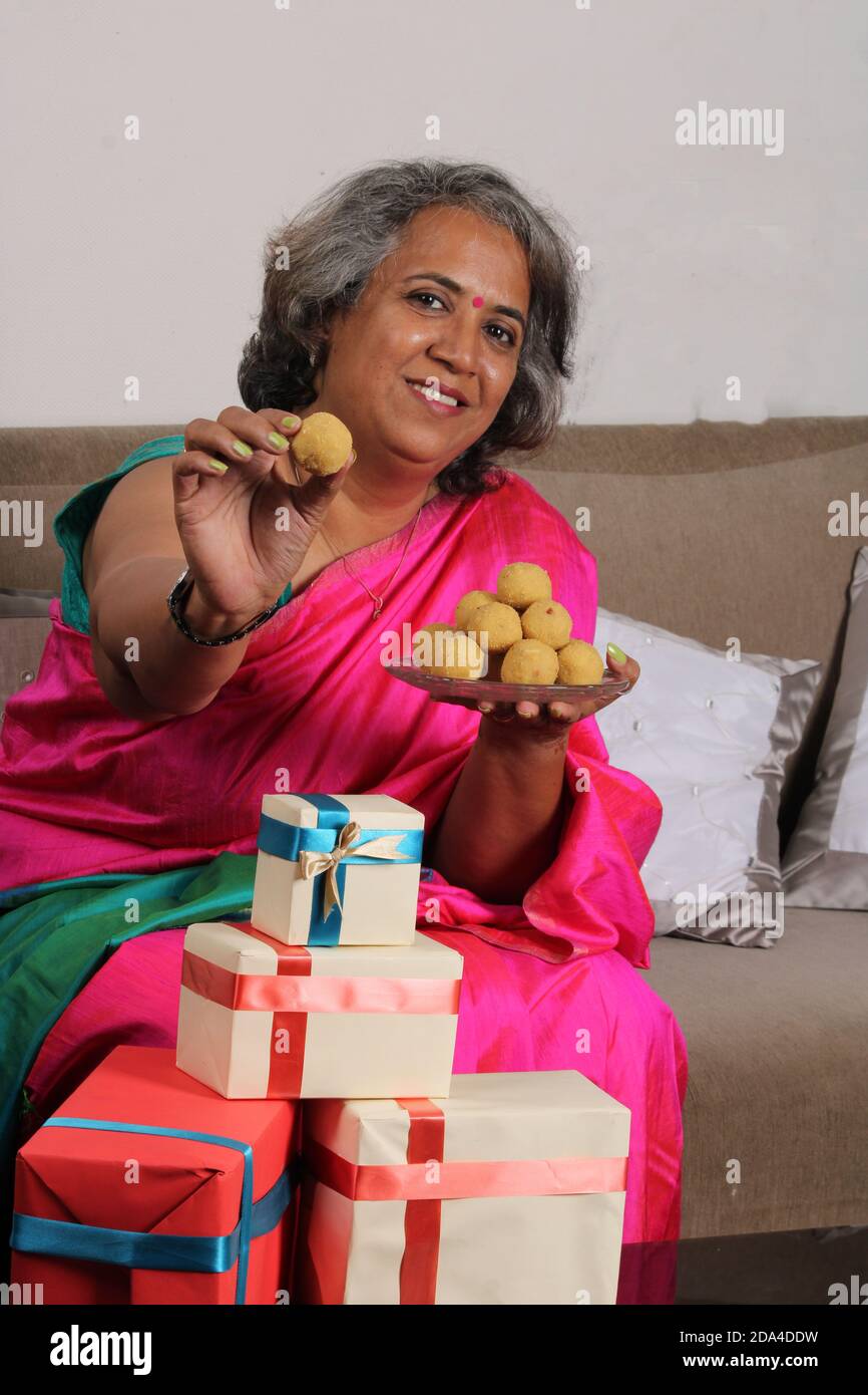 Femme indienne en saree / sari avec laddu et des boîtes cadeaux sur diwali / festival. Banque D'Images