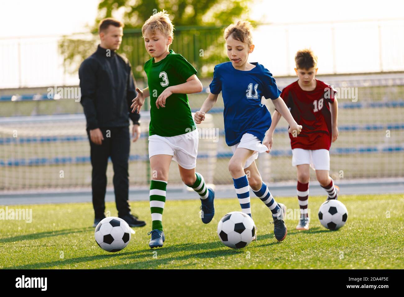 Jeunes garçons en train de courir sur l'entraînement de football. Happy Kids sur les sports de football. Enfants dans des chemises en jersey colorées Banque D'Images