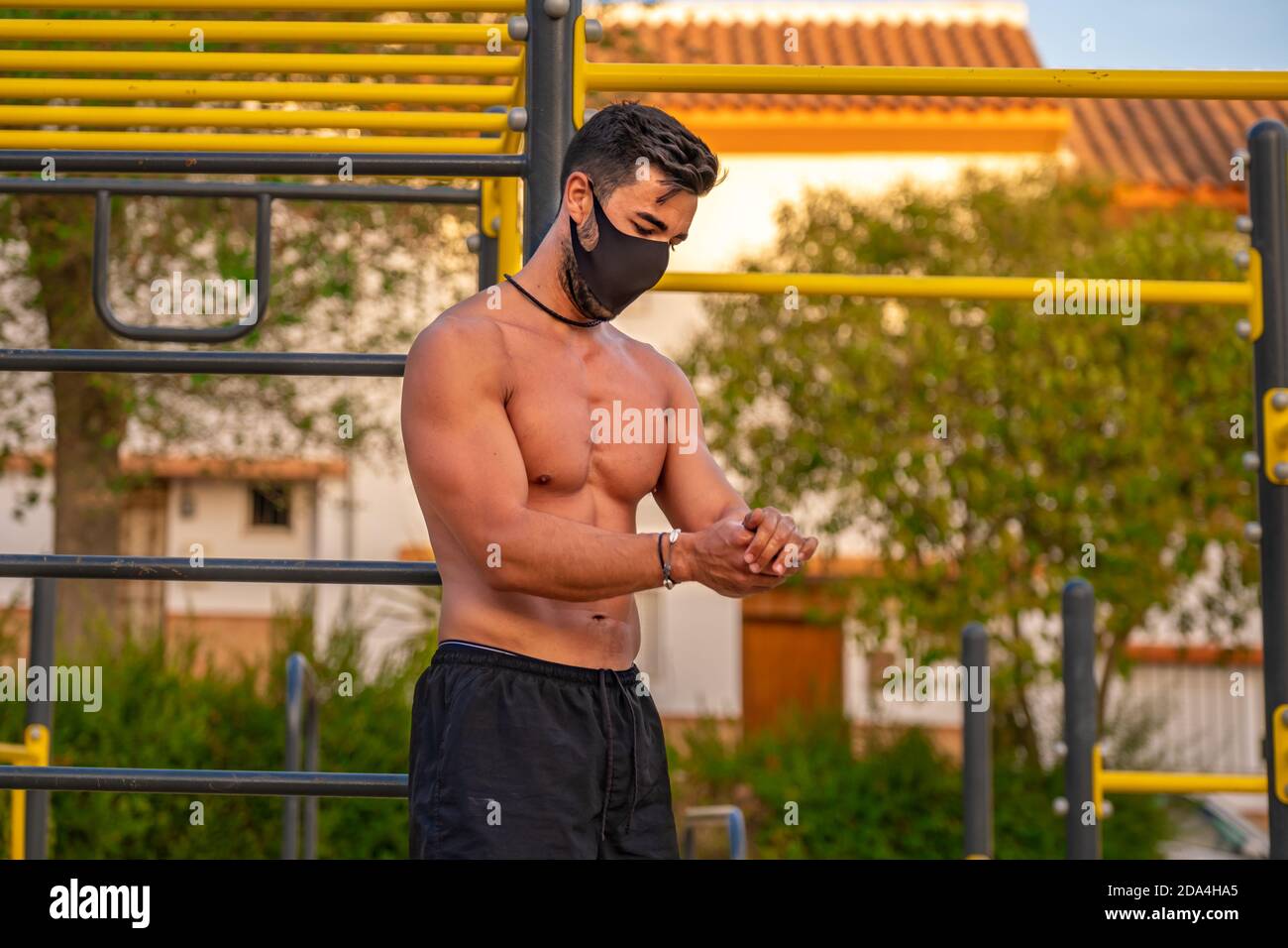 Jeune homme Latino sans chemise et pantalon noir et masque désinfectant ses  mains avec du gel hydroalcoolique pendant la formation un parc de  calisthéniques Photo Stock - Alamy