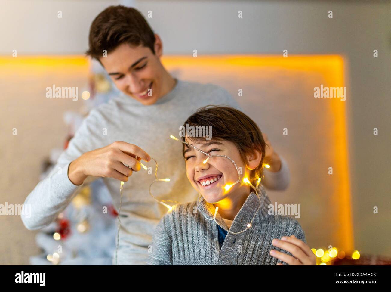 Deux frères jouant avec les lumières de Noël à la maison Banque D'Images
