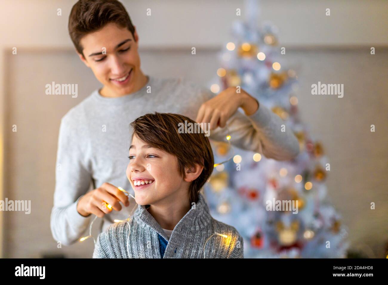 Deux frères jouant avec les lumières de Noël à la maison Banque D'Images