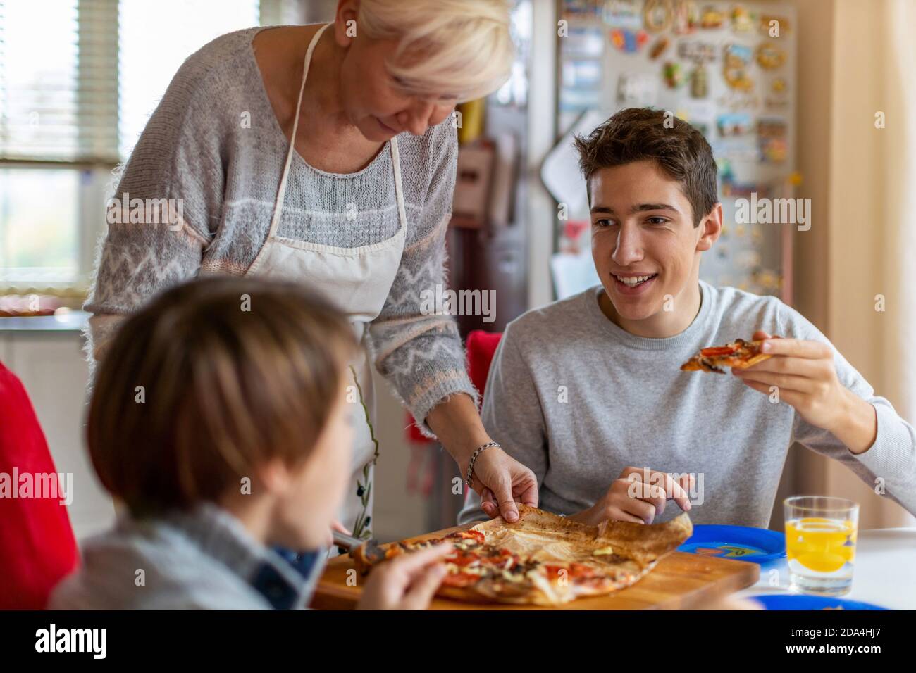 Mère et fils mangeant de la pizza pour le déjeuner à la maison Banque D'Images