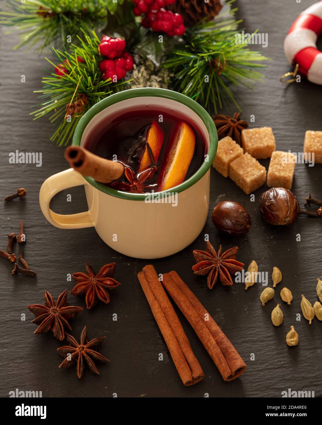 Vin chaud, alcool chaud en hiver, mug vintage, ingrédients orange et épices et décoration de Noël sur pierre noire, vue rapprochée. Banque D'Images