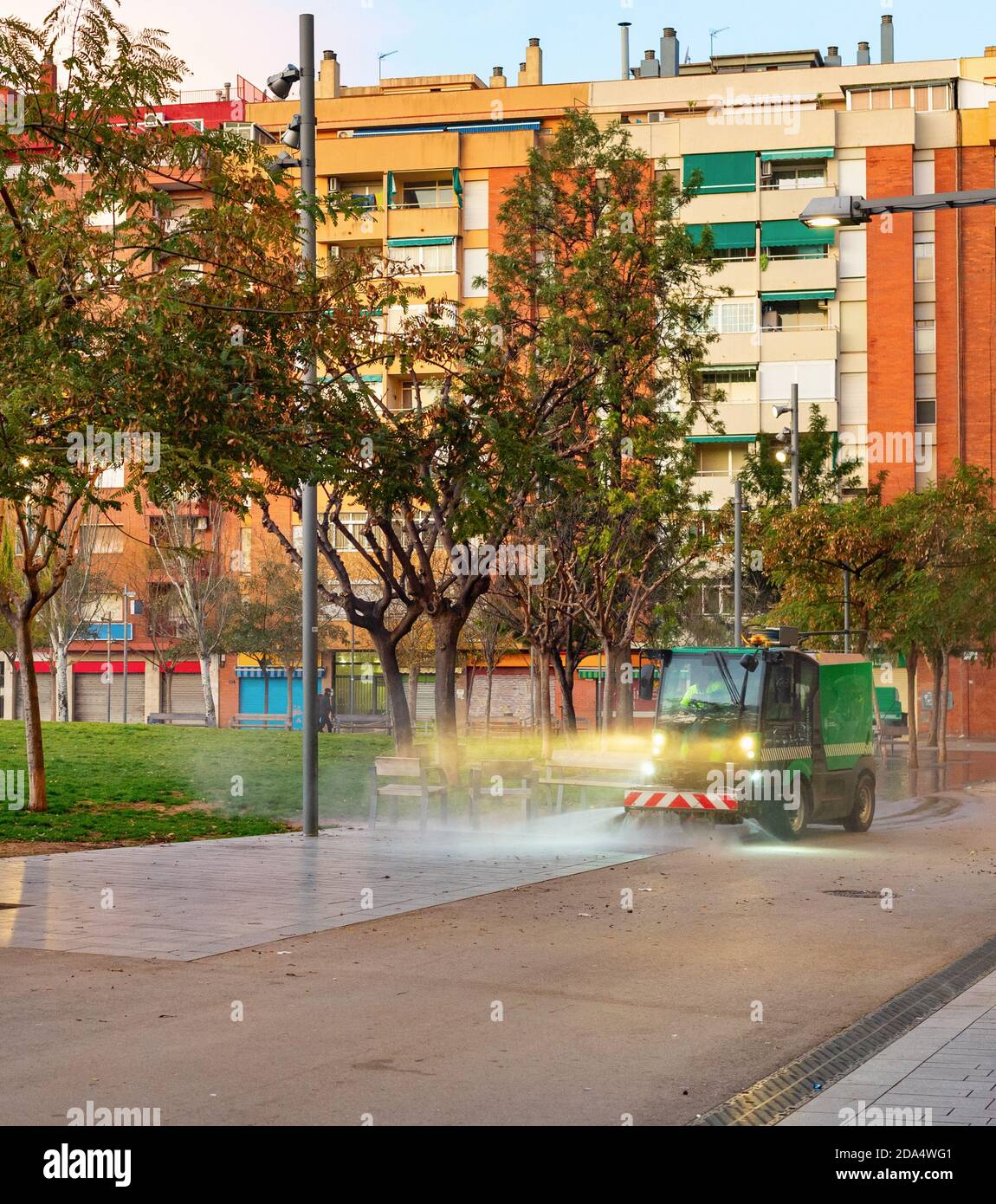 Arrosage machine de nettoyage rue par th.C. petit parc dans un quartier résidentiel avec des blocs d'appartements d'architecture moderne, Barcelone, Espagne Banque D'Images