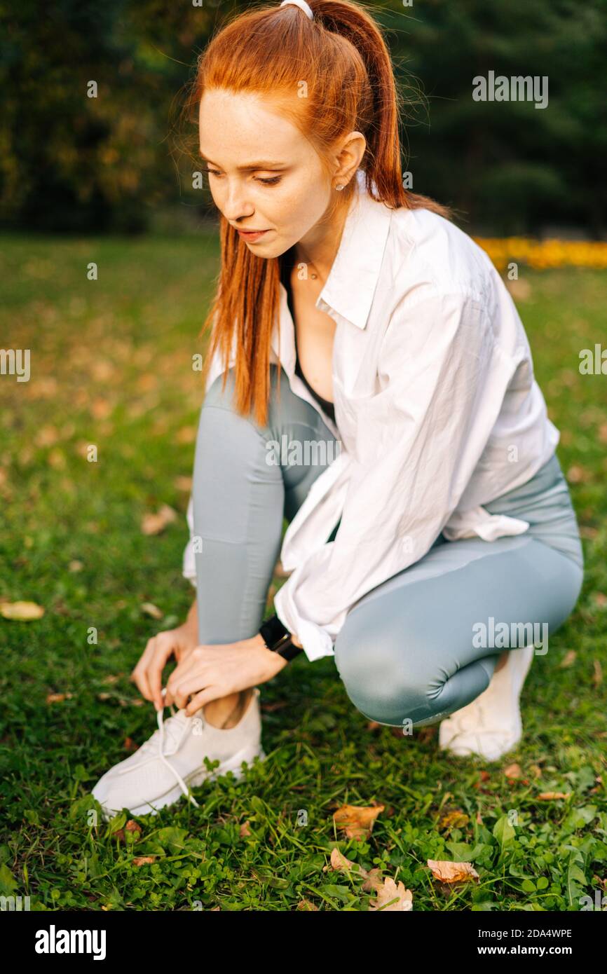 Jeune femme sportive à tête rouge nouant des lacets sur des baskets avant  de courir Photo Stock - Alamy