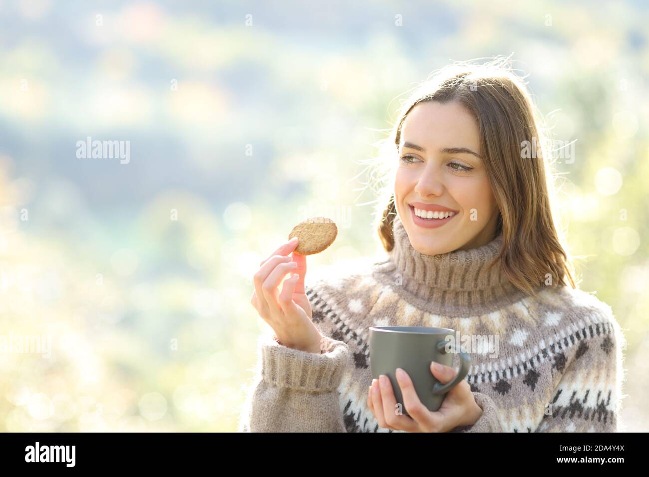 Bonne femme mangeant des biscuits et buvant du café dans la montagne en hiver Banque D'Images
